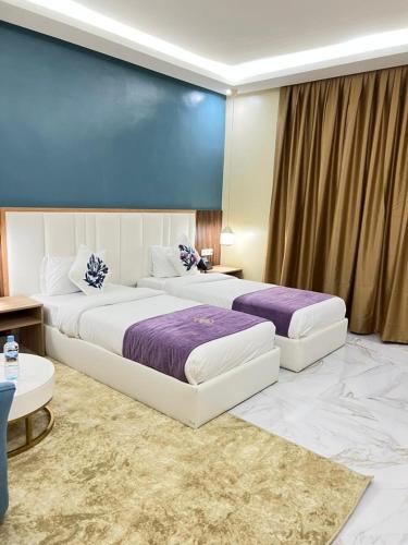 two beds in a hotel room with purple sheets at NOUAKCHOTT HOTEL Towva in Nouakchott