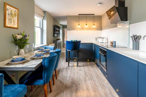 a kitchen with blue chairs and a long table at Silcox House Bath in Bath