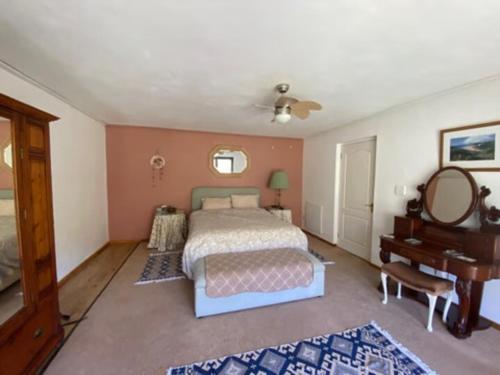 - une chambre avec un lit, un miroir et un piano dans l'établissement Jennys Farm Cottage, à Robertson