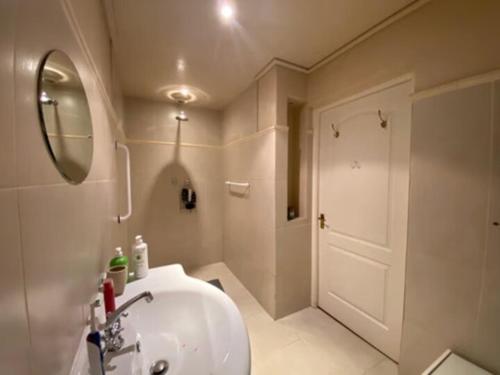 La salle de bains est pourvue d'un lavabo, d'un miroir et d'une porte. dans l'établissement Jennys Farm Cottage, à Robertson
