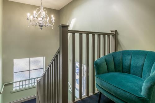 a staircase with a green chair and a chandelier at Silcox House Bath in Bath