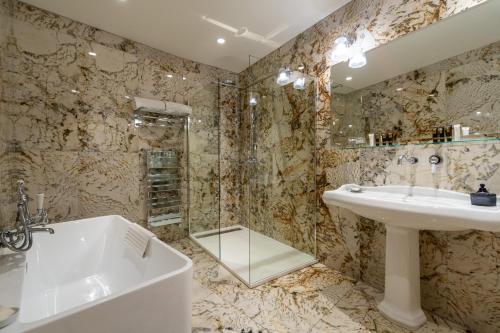 a bathroom with a sink and a shower and a tub at Hôtel Demeure Loredana in Saint-Florent