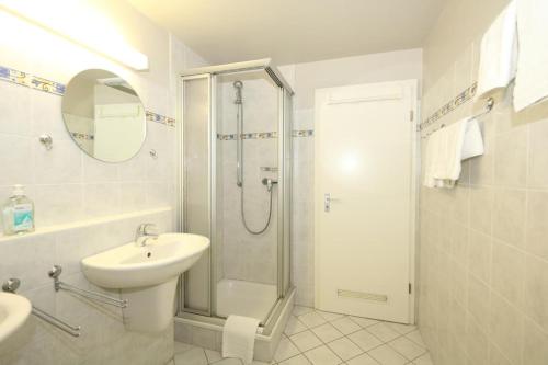 a white bathroom with a shower and a sink at Bangert - Haus Cäcilia in Wenningstedt