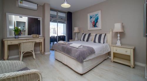 1 dormitorio con cama, escritorio, mesa y sillas en 402 ipanema, en Durban