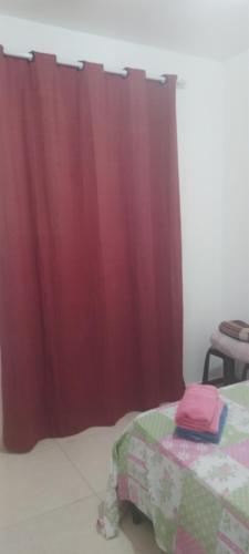 a bedroom with a red curtain and a bed with a table at Casa suite airport in Campinas