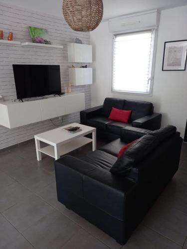 - un salon avec un canapé noir et une table blanche dans l'établissement Le Petit Choiseul - Superb bungalow sleeps 6, à Amboise