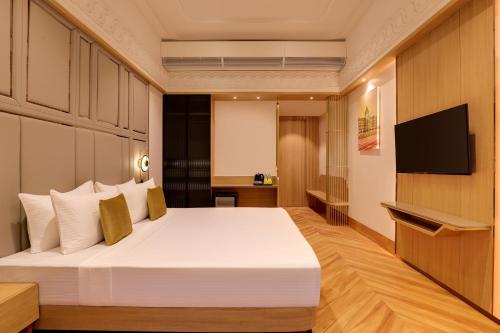 a bedroom with a large bed and a flat screen tv at Lemon Tree Hotel, Mira Road, Mumbai in Sasupāda