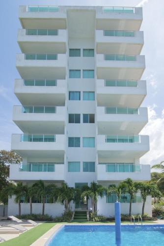 a tall white building with a swimming pool in front of it at Magico Apartamento Frente al Mar 2 Habitaciones B11B in Coveñitas