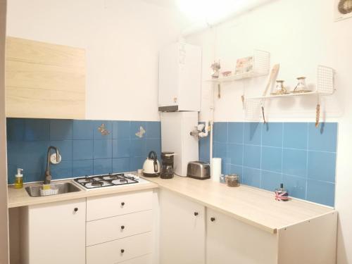 a kitchen with white cabinets and blue tiles at SMB Studio Poarta Schei in Braşov