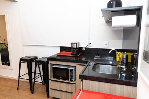 a small kitchen with a sink and a microwave at Guaja 745 - Apartamento Luna in Belo Horizonte