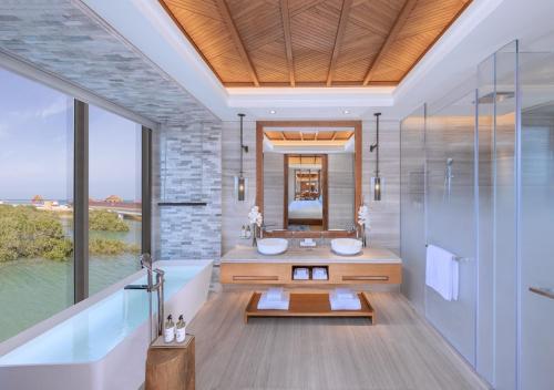 a bathroom with two sinks and a tub and a mirror at Anantara Mina Ras Al Khaimah Resort in Ras al Khaimah
