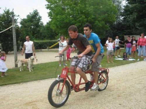 two young men riding a small bike in a park at Camping 4 étoiles - Piscine - ccb0bif in Apremont