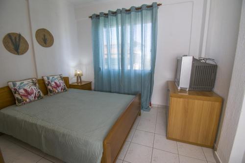 a small bedroom with a bed and a television at Alma House by RentalsPro - Nea Flogita Halkidiki in Flogita