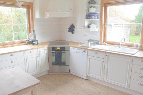 a kitchen with white cabinets and a sink and windows at Between the dunes and the sea in Les Moitiers-dʼAllonne