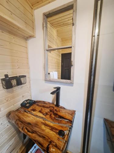 a room with a log on the wall and a mirror at Casa de pe Lac - La noi la munte in Mătişeşti