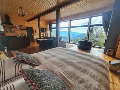a bedroom with a large bed with a large window at Casa de pe Lac - La noi la munte in Mătişeşti