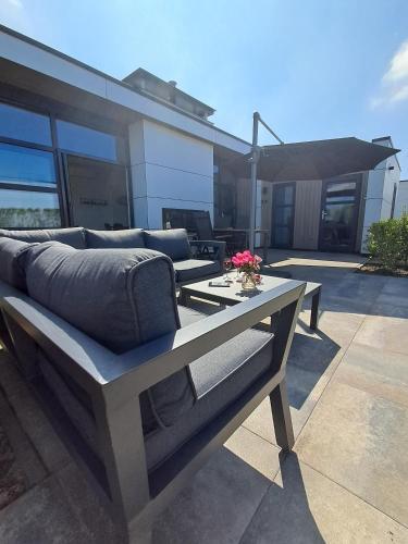 a couch sitting on top of a patio at Marina Strandbad Chalet Land in Sicht mit Zaun Haus Nr 81 in Olburgen