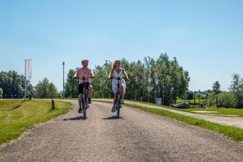 two girls riding bikes down a gravel road at Marina Strandbad Chalet Land in Sicht mit Zaun Haus Nr 81 in Olburgen