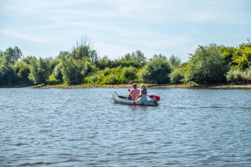 two people sitting in a boat on a lake at Marina Strandbad Chalet Land in Sicht mit Zaun Haus Nr 81 in Olburgen