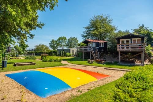 a playground with a house and a colorful play area at Marina Strandbad Chalet Land in Sicht mit Zaun Haus Nr 81 in Olburgen