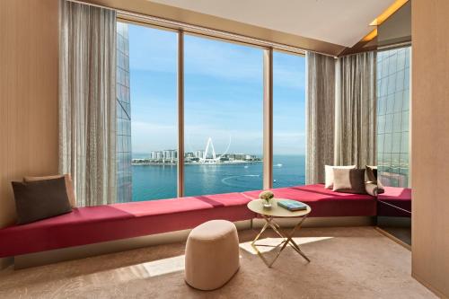 a bedroom with a large window with a red bed and a table at Rixos Premium Dubai JBR in Dubai
