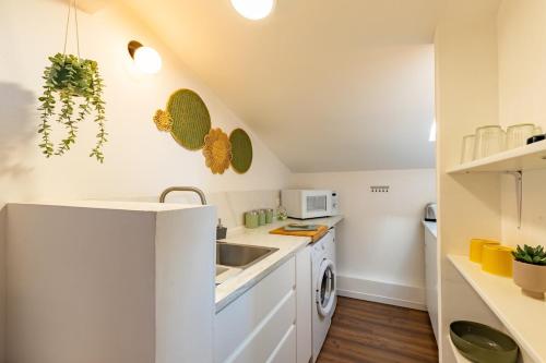 une petite cuisine avec des armoires blanches et un évier dans l'établissement Les Toits de Roquelaine - Bright & cozy studio, à Toulouse