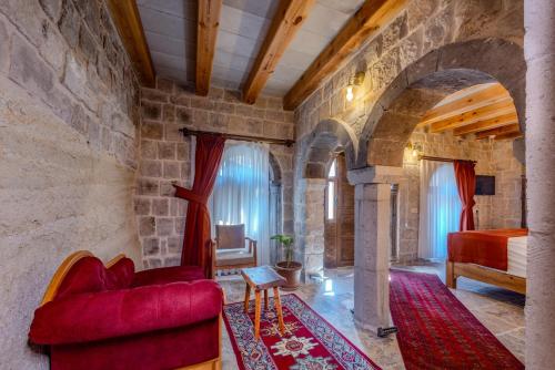 a living room with a red couch and a bed at Gala Cave Cappadocia in Goreme