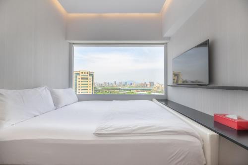 a bedroom with a large white bed and a window at citizenM Taipei North Gate in Taipei