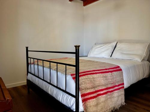 a bedroom with a bed with a black frame and white sheets at Casa das Histórias in Pinhel