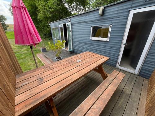 a picnic table on a deck with an umbrella at Gite "home" - piscine in Juvigny-le-Tertre