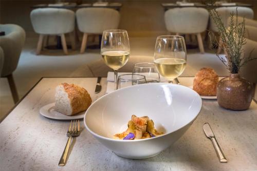 un tavolo con una ciotola di cibo e due bicchieri di vino di Barceló Bilbao Nervión a Bilbao