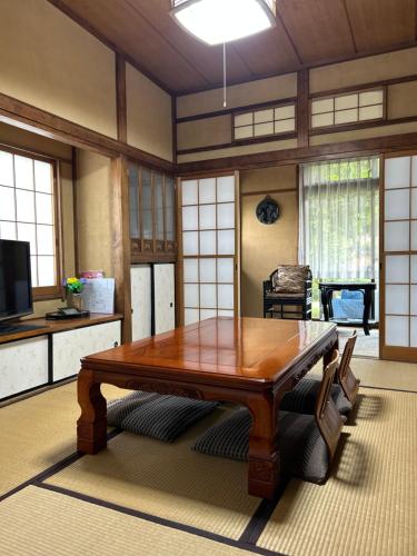 a living room with a wooden table and a tv at Chiba Homestay by Lek บ้านพักใกล้นาริตะโตเกียว in Yotsukaidō
