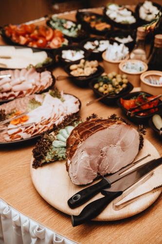 a table topped with plates of food with meat and vegetables at Pensjonat Witoldówka in Krynica Zdrój