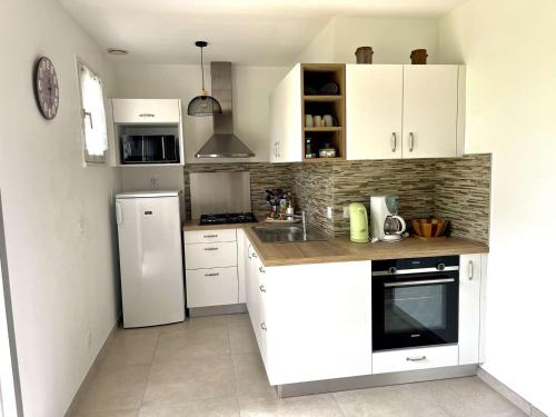 une cuisine avec des armoires blanches et un réfrigérateur blanc dans l'établissement Maison 5 pièces calme proche plage avec jardin, animaux acceptés - FR-1-479-186, à Erdeven