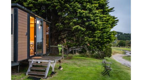 a tiny house with a bench and a tree at Tiny House Big View 1 by Tiny Away in Boneo