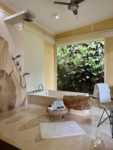 a bathroom with a tub and a large window at BATI Private Living in Ubud