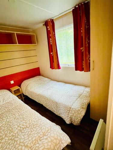 une petite chambre avec deux lits et une fenêtre dans l'établissement Mobil-home 159 camping Les Clarines, à La Bourboule