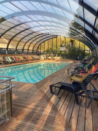 une piscine avec des chaises longues et une verrière dans l'établissement Mobil-home 159 camping Les Clarines, à La Bourboule