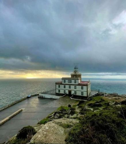 a lighthouse sitting on the edge of the ocean at Amodiño- 1º línea Playa Langosteira y vistas al mar in Fisterra
