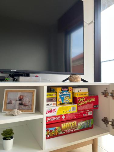 a shelf with books and a television on top at Amodiño- 1º línea Playa Langosteira y vistas al mar in Fisterra