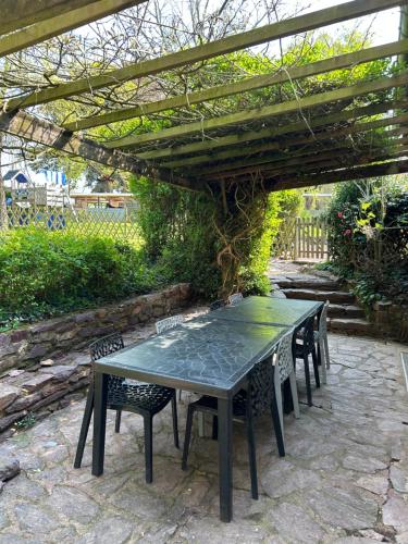 une table et des chaises sous une pergola en bois dans l'établissement Gites du Charme, à Mauron