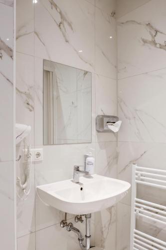 a white bathroom with a sink and a mirror at Sleephotels Alsterroom in Hamburg