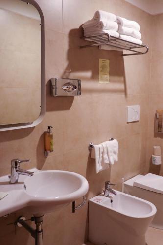a bathroom with a sink and a toilet and a mirror at Monica Hotel Fiera in Pregnana Milanese