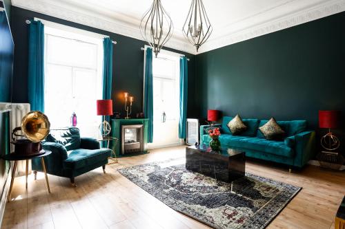 a living room with green walls and blue furniture at Sleephotels Alsterroom in Hamburg