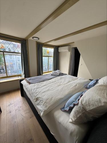 Un dormitorio con una cama grande y dos ventanas. en The Hazel House, en Haarlem