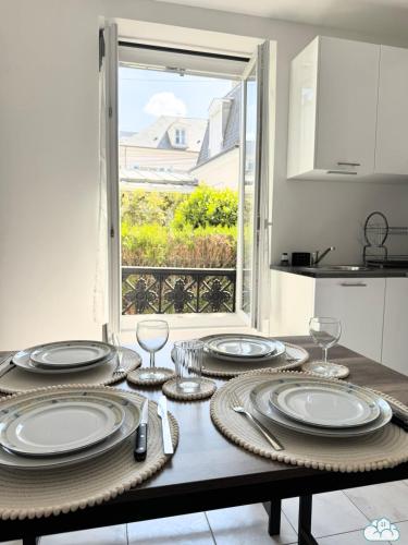 - une table avec des assiettes et des verres dans la cuisine dans l'établissement Au Fil de la Marne à 15mn Disney et 25mn Paris, à Lagny-sur-Marne