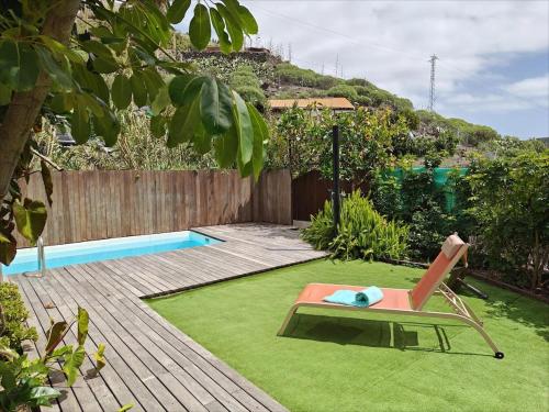 a yard with a lawn with a chair and a pool at El Alpendre- Entre plataneras, a 10 minutos playa in Arucas