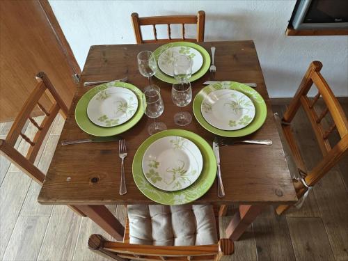 a wooden table with green plates and wine glasses on it at El Alpendre- Entre plataneras, a 10 minutos playa in Arucas