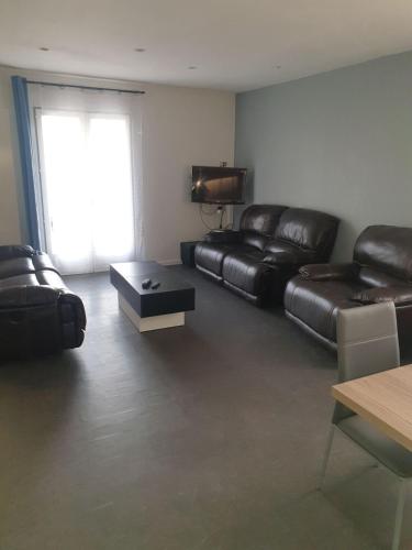 a living room with black leather furniture and a window at Maison 7 personnes in Gouttières