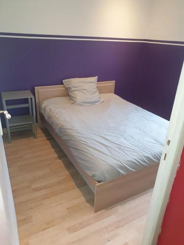 Ce lit se trouve dans un dortoir doté d'un mur violet. dans l'établissement Maison 7 personnes, à Gouttières